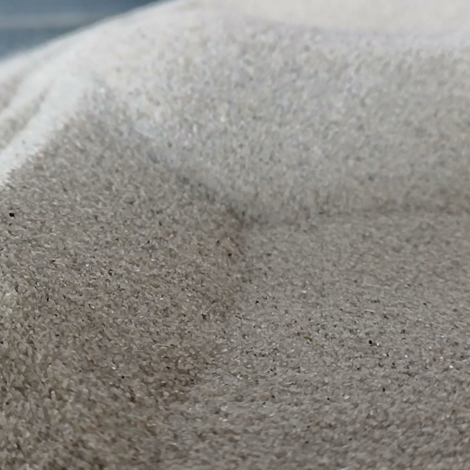 Chinchillasand Naturgrau, 0,1–0,3 mm, 10 kg: Geschwungene Vertiefung zwischen grauen Sandkanten.