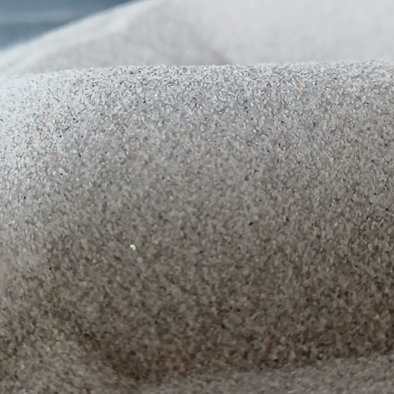 Chinchillasand Naturgrau, 0,1–0,3 mm, 5 kg: Graue Kornstruktur auf einer erhöhten Vorderkante.