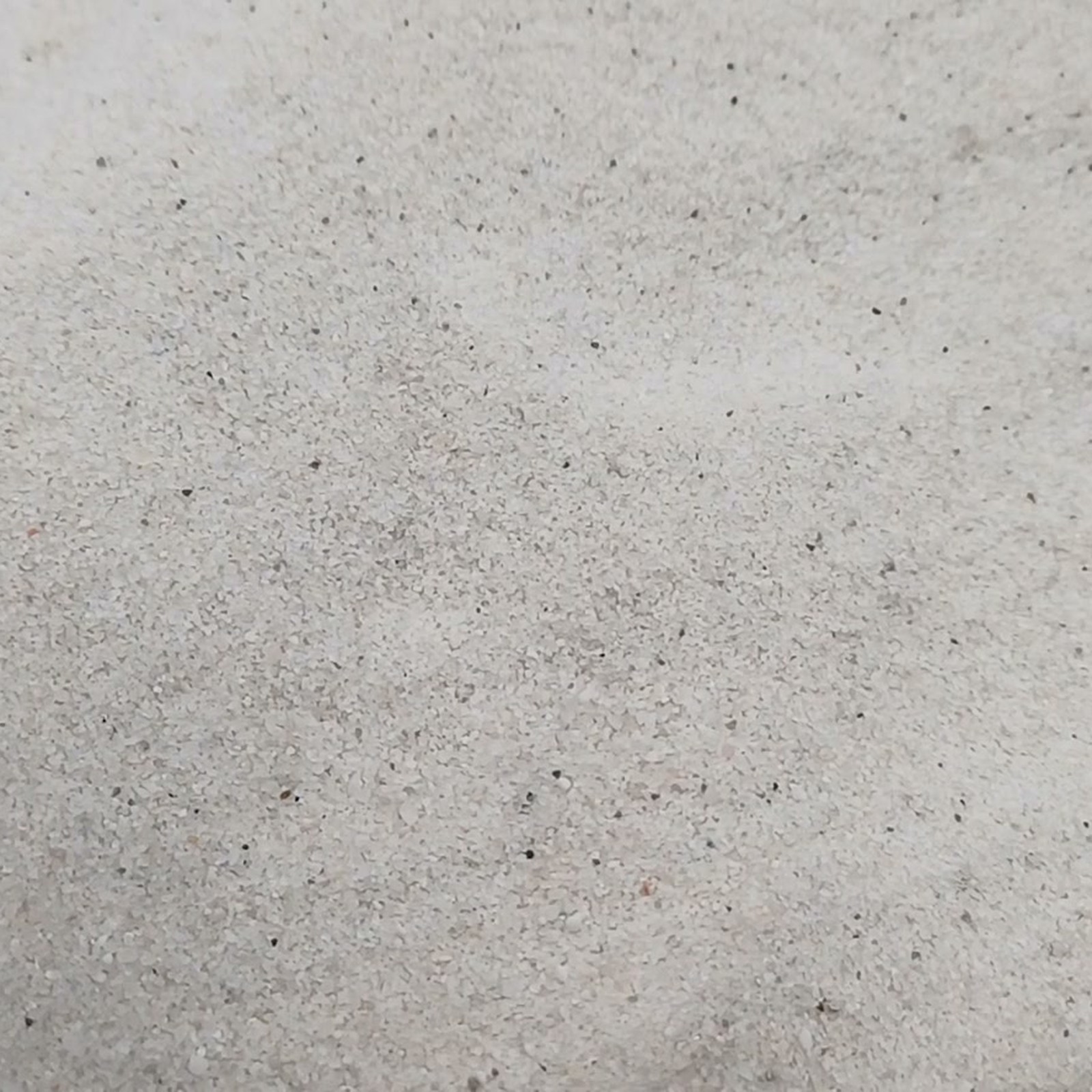 Flache Sandfläche mit feinen Körnern und vereinzelten dunklen Sprenkeln – Quarzsand Naturweiß für das Aquarium, 0,1–0,4 mm, 25 kg.