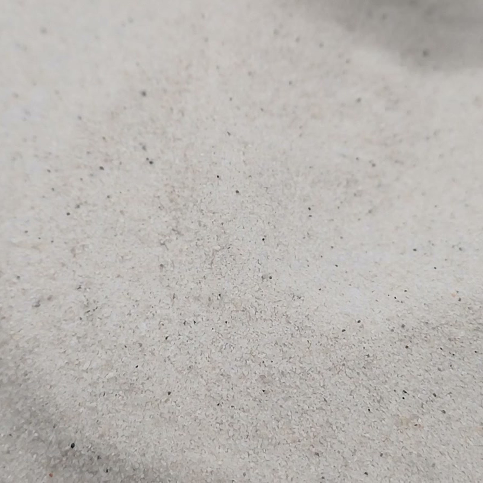 Feine Kornstruktur auf einer hellen Fläche mit flachen Sandwellen – Quarzsand Naturweiß für das Aquarium, 0,1–0,4 mm, 25 kg.