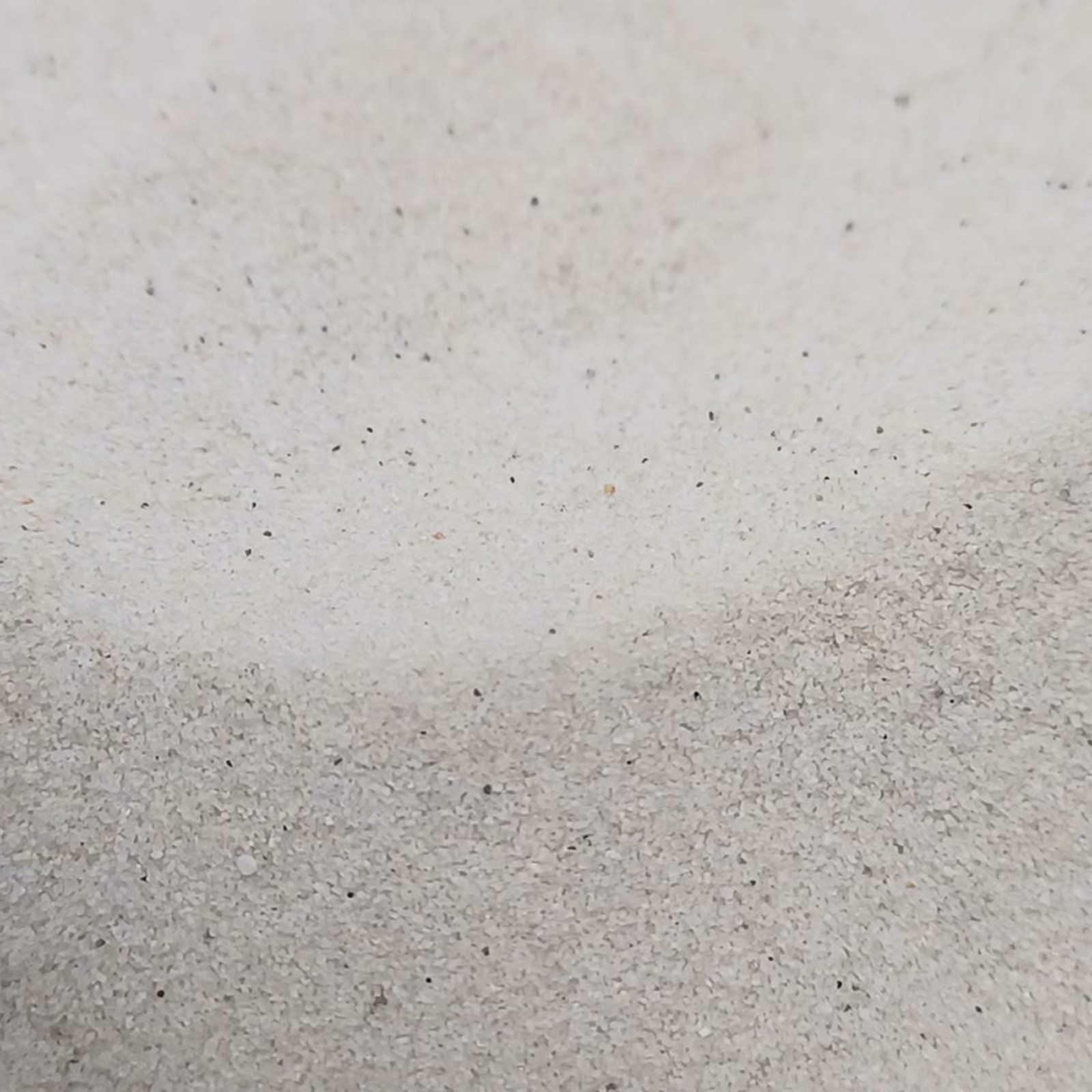 Sandoberfläche mit sanften Wölbungen und einzelnen dunklen Körnern – Quarzsand Naturweiß für das Aquarium, 0,1–0,4 mm, 25 kg.