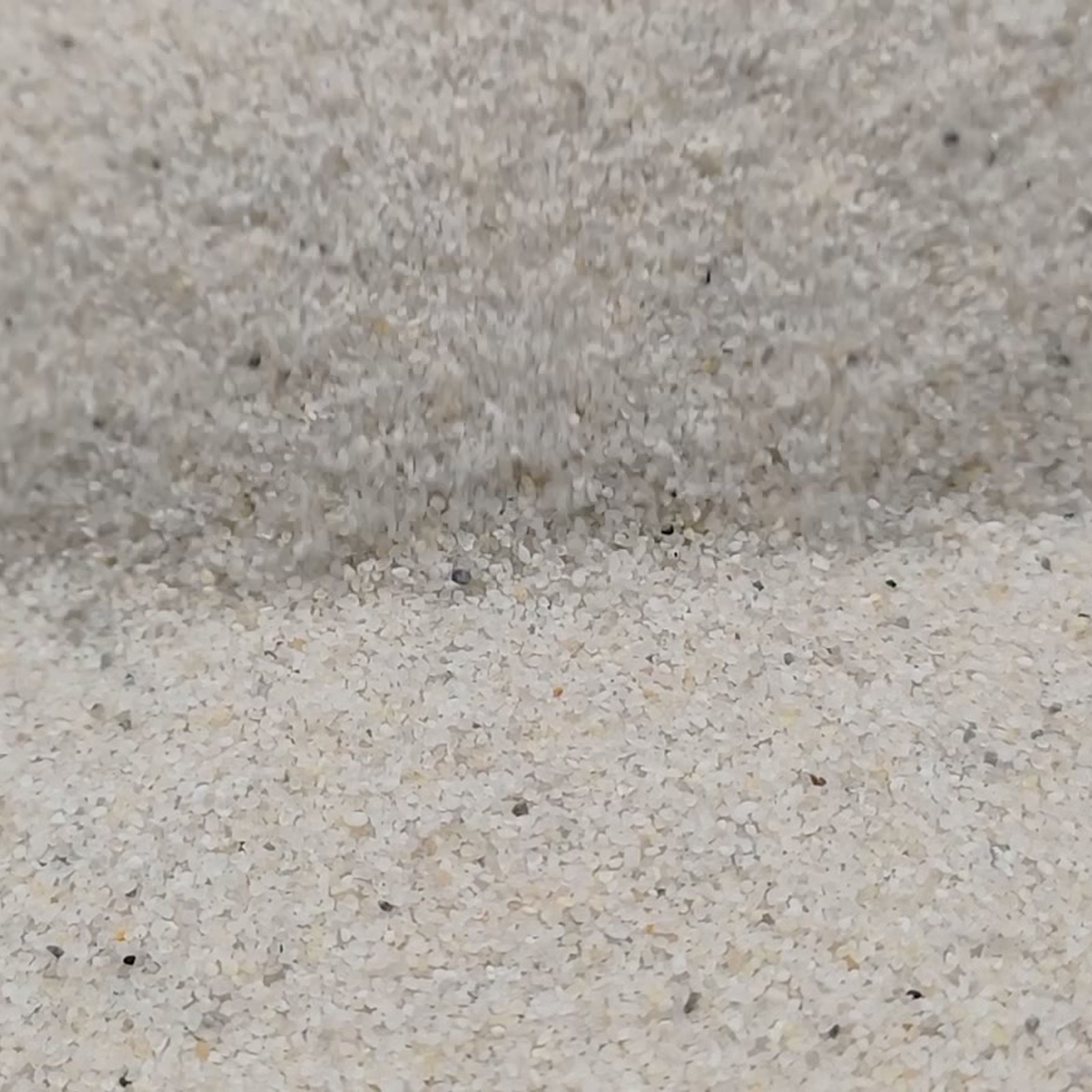 Vogelsand Naturweiß, 0,2–0,5 mm, 20 kg: Mulde unter einer erhöhten Sandkante.