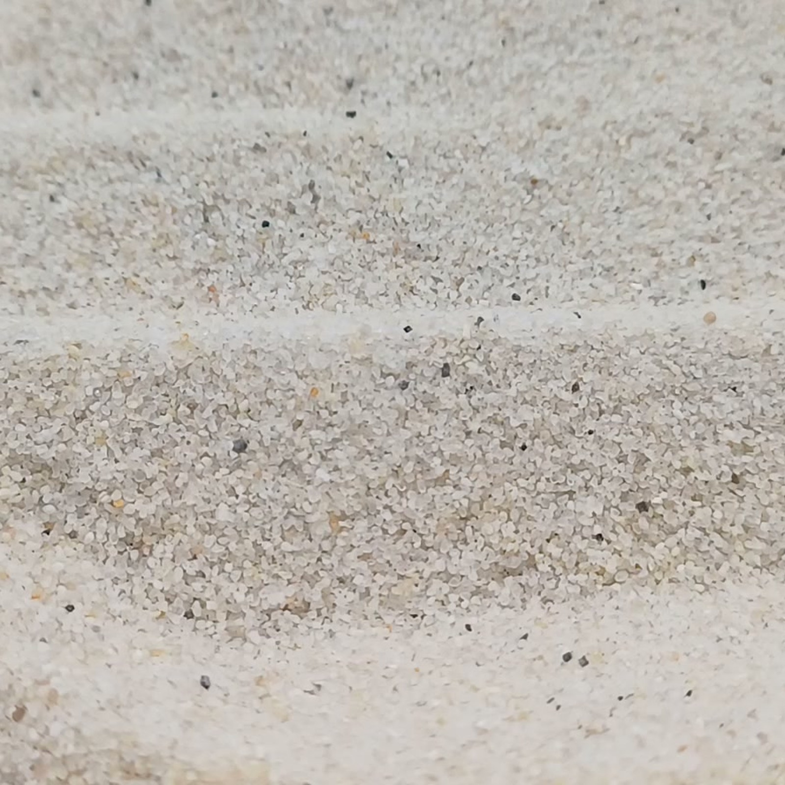 Aquariumsand Naturweiß, 0,2–0,5 mm, 25 kg: Drei flache Sandwellen in Nahaufnahme.