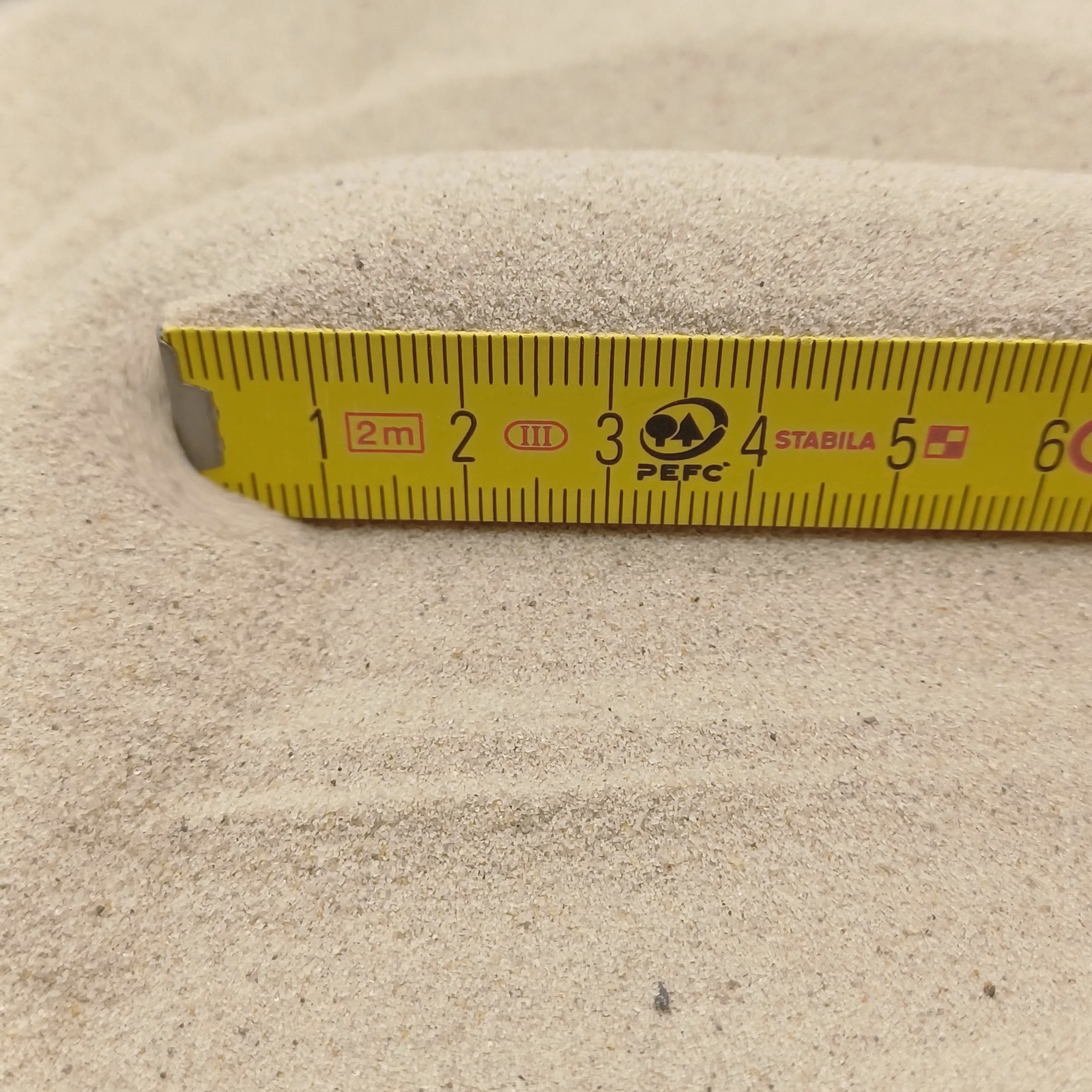 Aquariumsand Naturbeige, 0,1–0,4 mm, 25 kg: Körnung am gelben Maßstab.
