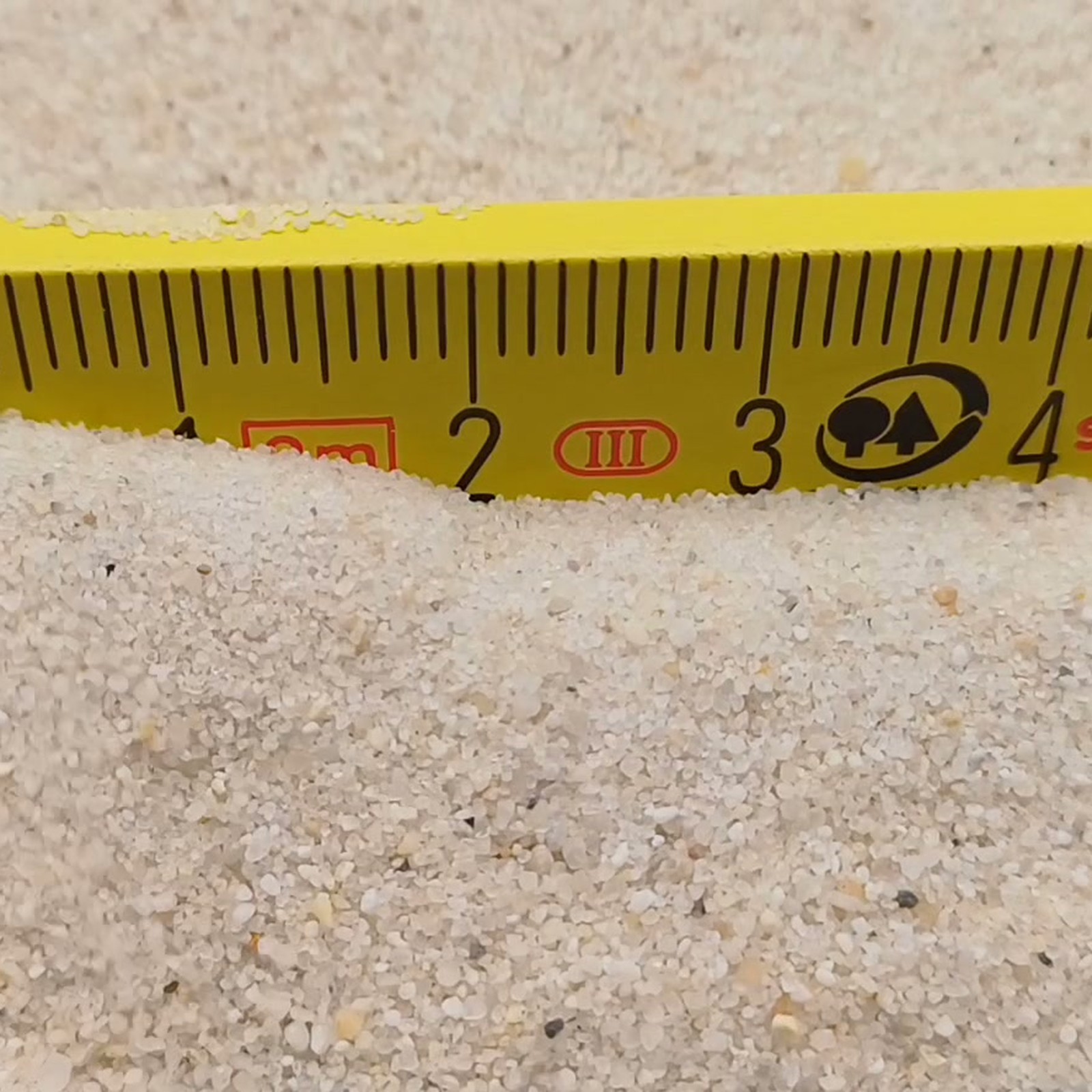 Industriesand Naturweiß, 0,1–0,6 mm, 25 kg: Heller Sandrücken direkt vor dem Gliedermaßstab.
