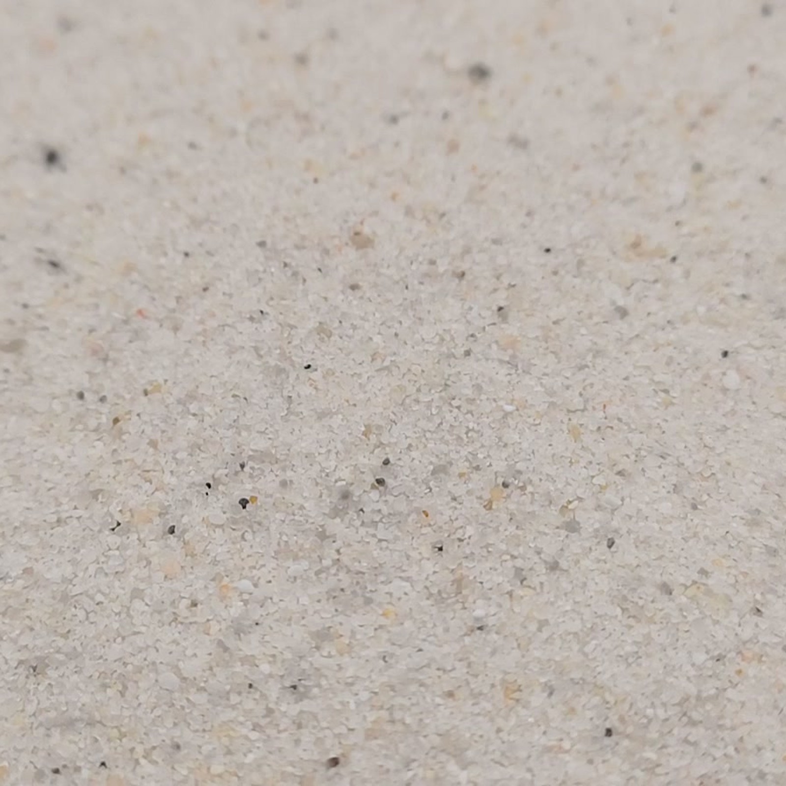 Industriesand Naturweiß, 0,1–0,6 mm, 25 kg: Nahaufnahme einer hellen Sandmulde.