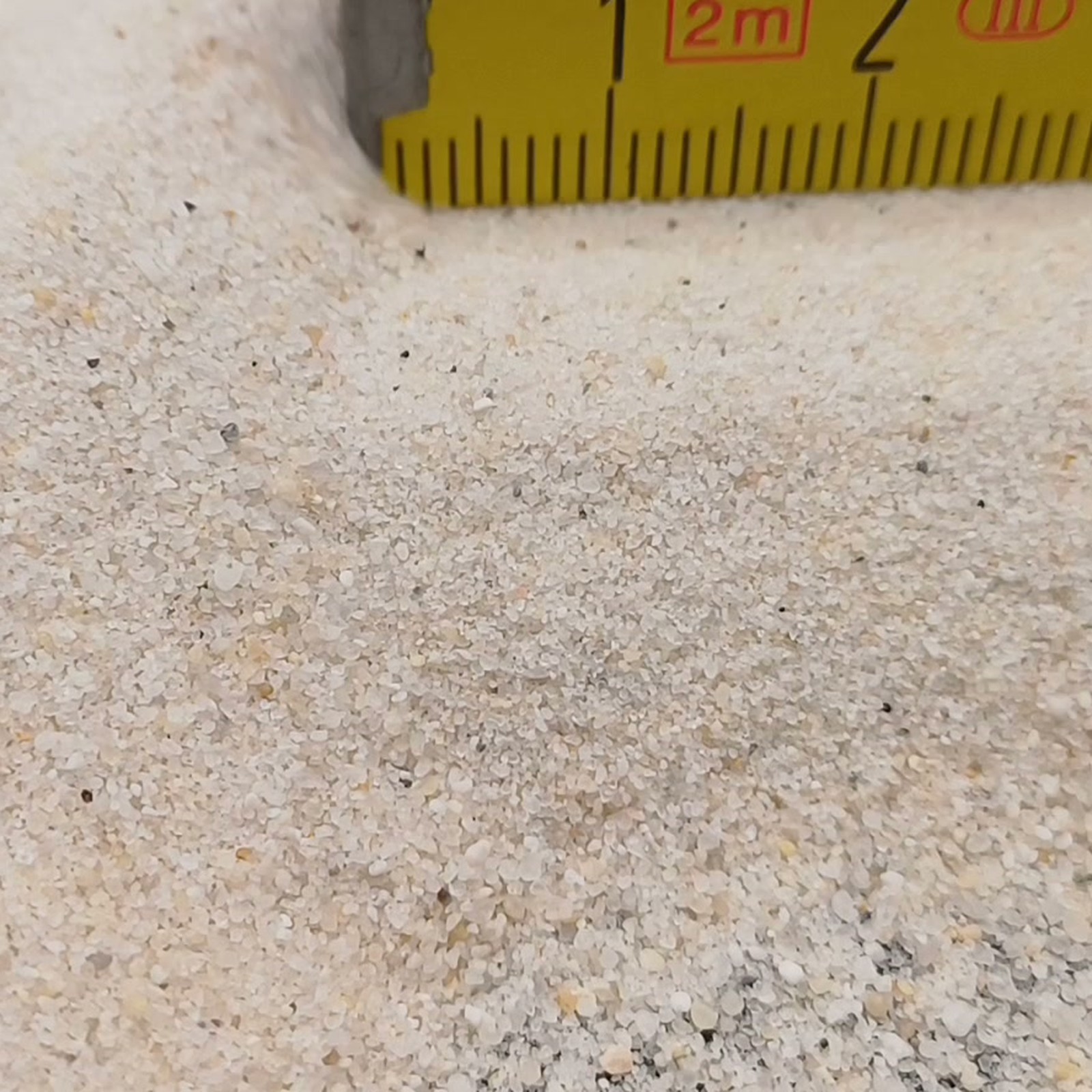 Industriesand Naturweiß, 0,1–0,6 mm, 25 kg: Kornfläche vor einem teilweise sichtbaren Gliedermaßstab.