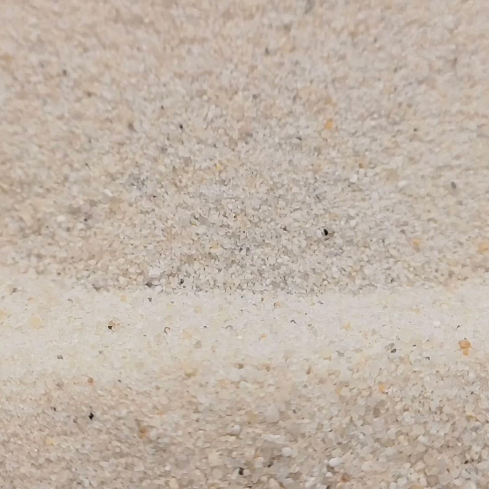 Industriesand Naturweiß, 0,1–0,6 mm, 25 kg: Geschwungene Sandwelle in Nahaufnahme.