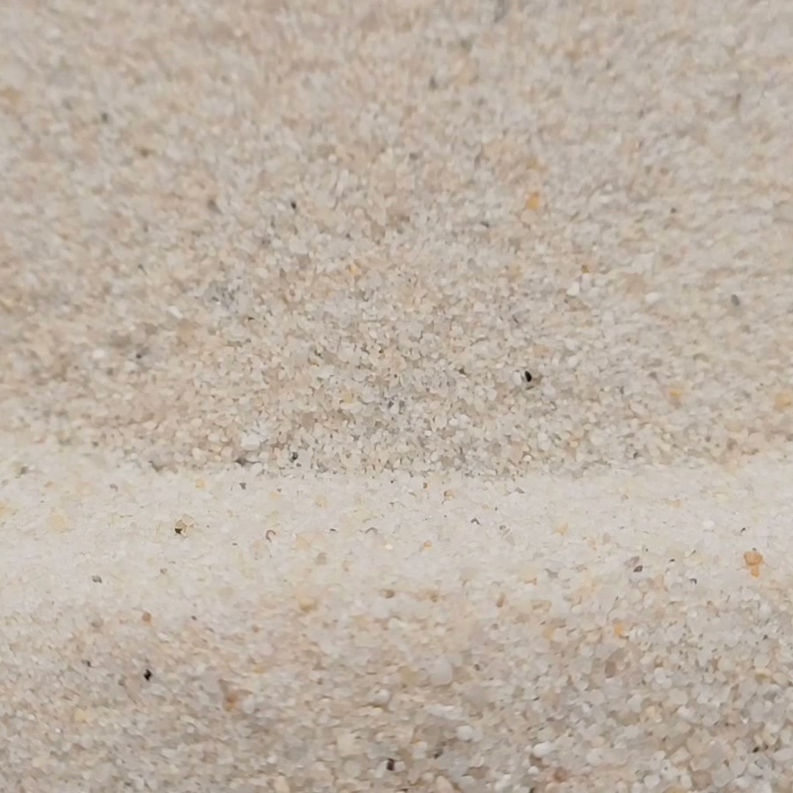 Industriesand Naturweiß, 0,1–0,6 mm, 25 kg: Flache Mulde mit grobkörnigerem Vordergrund.