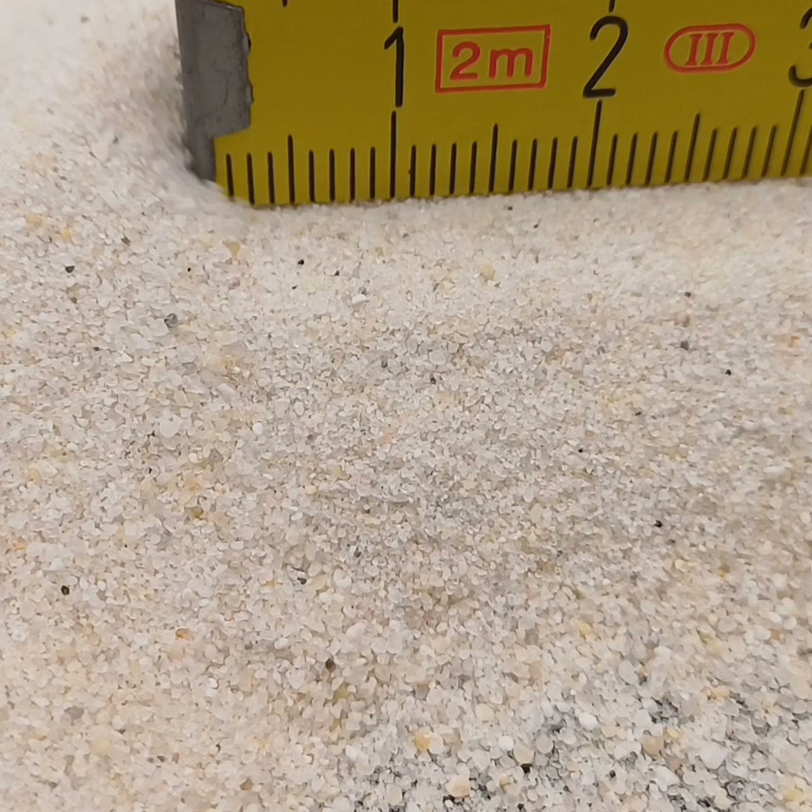 Industriesand Naturweiß, 0,1–0,6 mm, 25 kg: Zusätzliche Kornansicht am Ende des gelben Maßstabs.