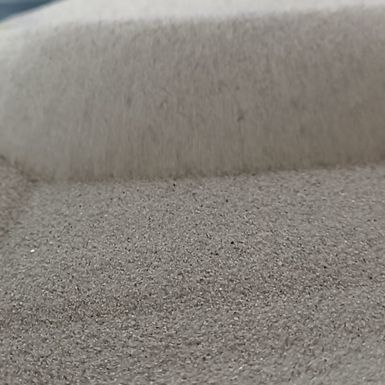 Vogelsand Naturgrau, 0,1–0,4 mm, 25 kg: Kornfläche vor steiler Sandkante.