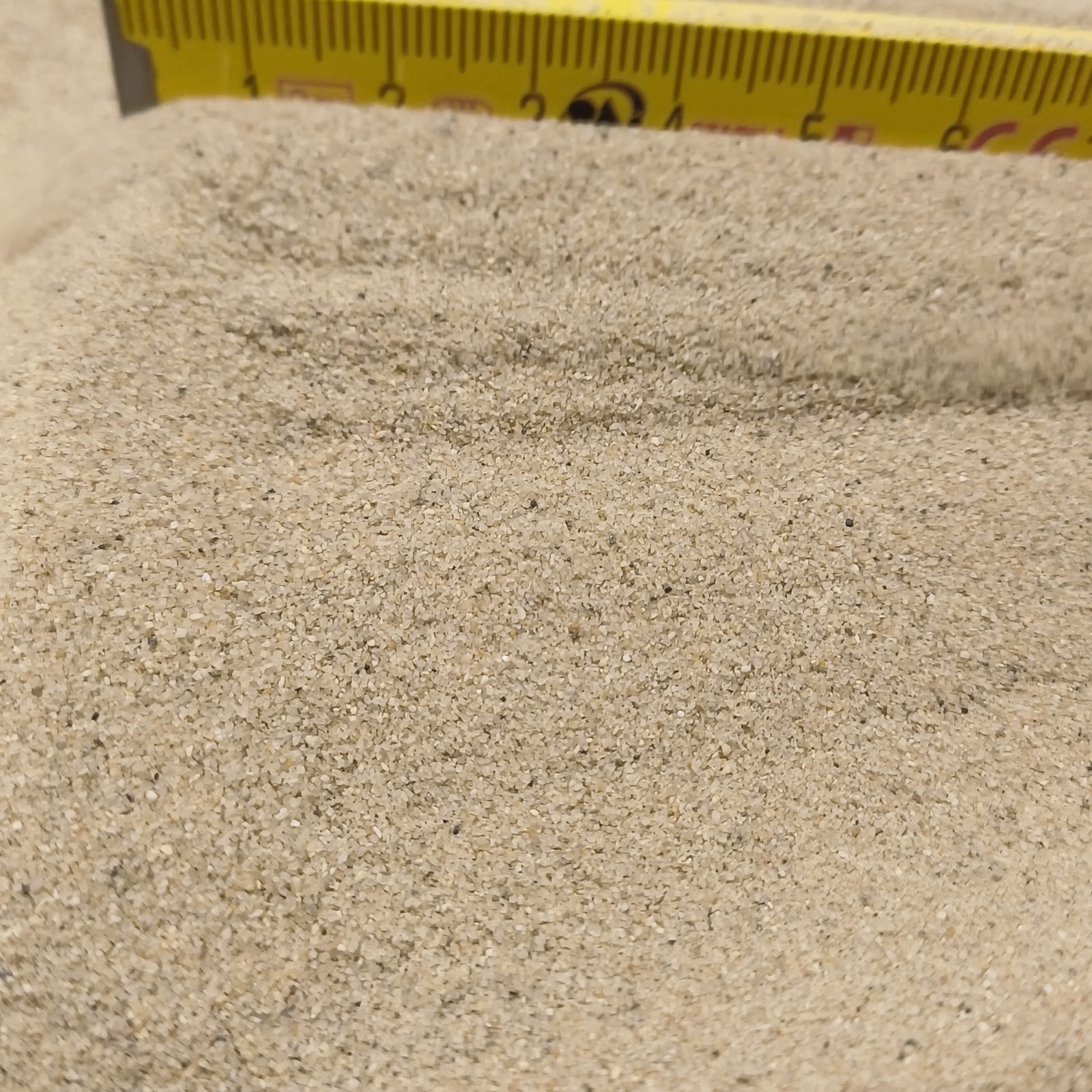 Aquariumsand Naturbeige, 0,1–0,5 mm, 6,3 kg: Mehrere Sandwellen vor einem gelben Maßstab.