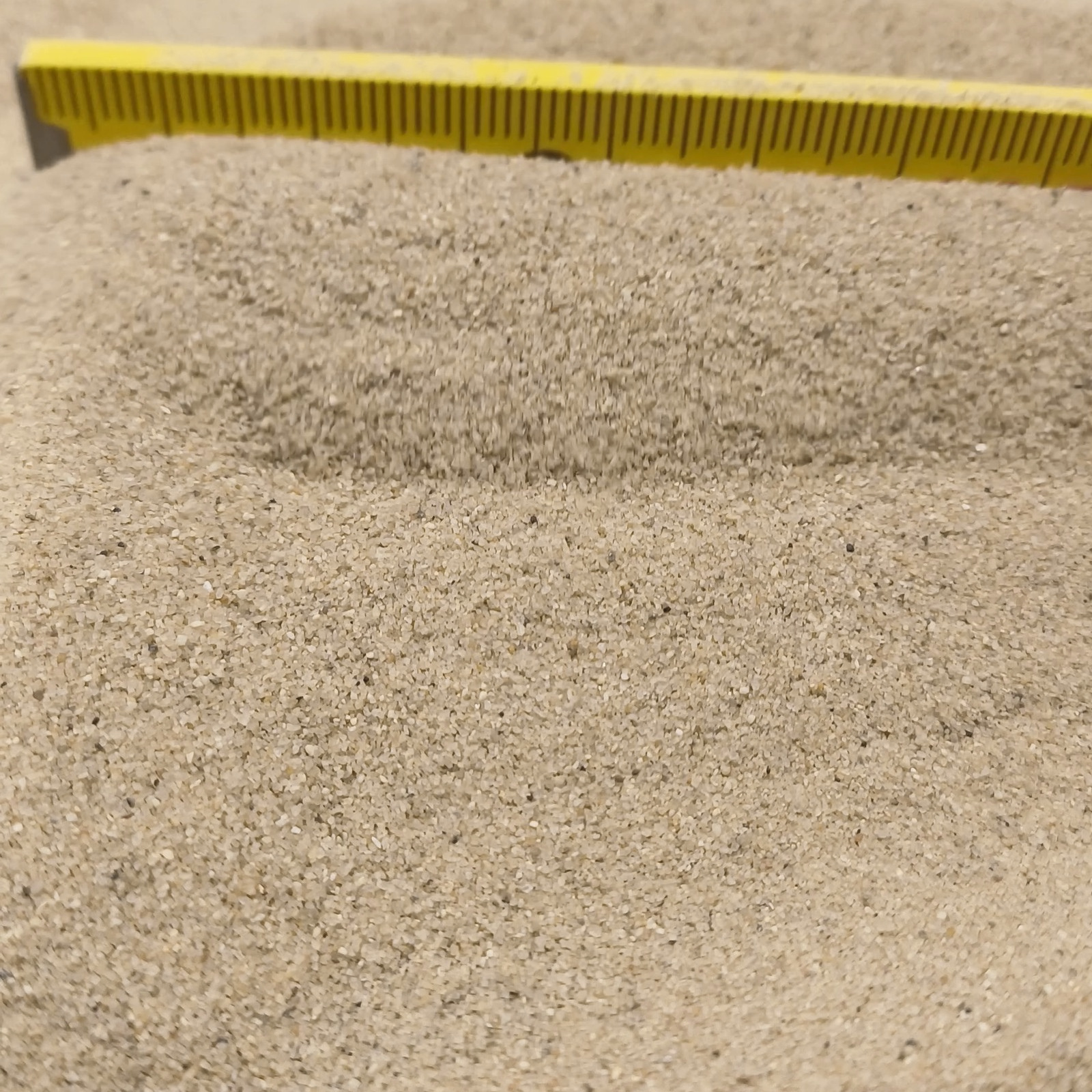 Aquariumsand Naturbeige, 0,1–0,5 mm, 6,3 kg: Zwei Sandrücken mit gelbem Maßstab im Hintergrund.