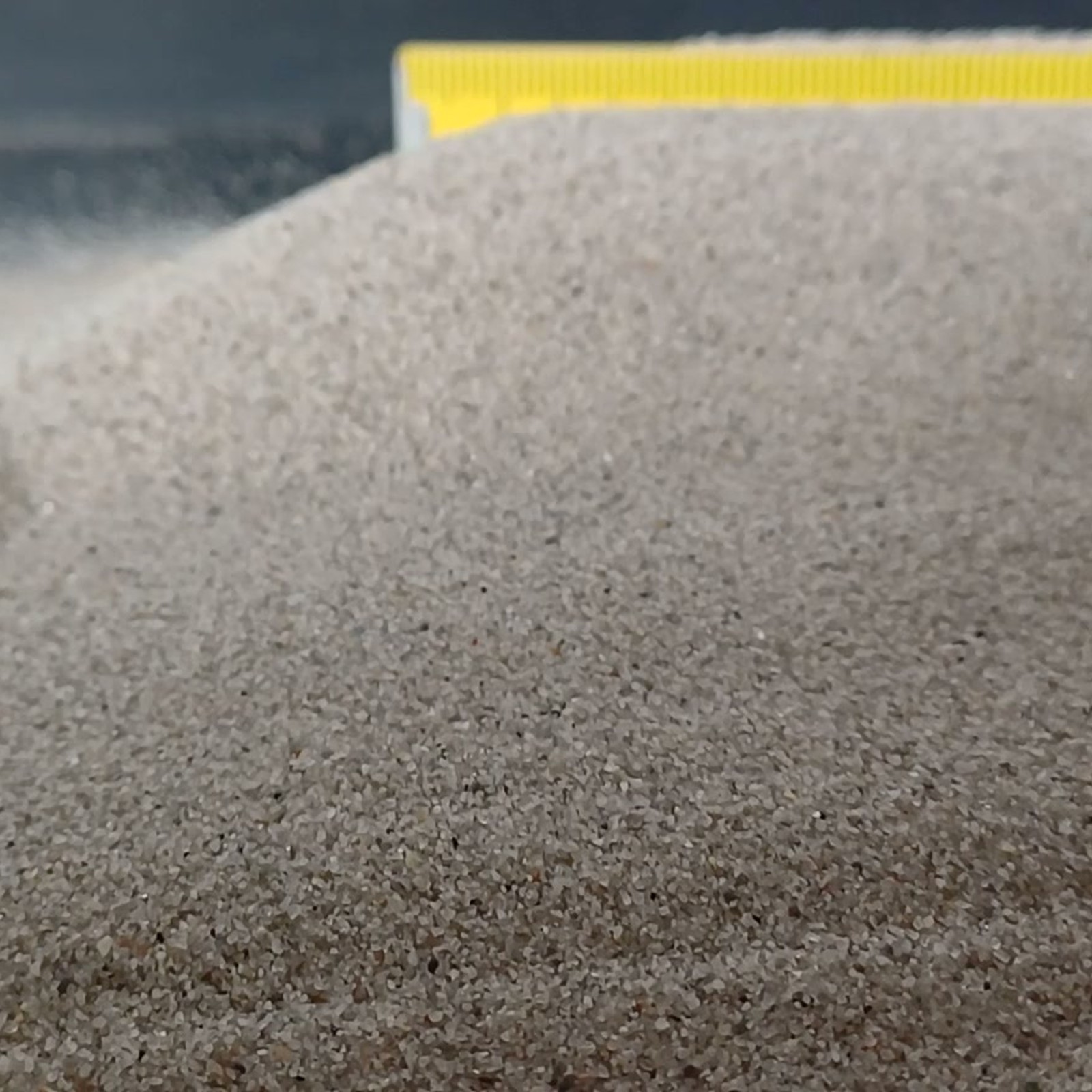 Aquariumsand Naturgrau, 0,1–0,5 mm, 10 kg: Gewölbter Sandrücken mit Maßstab im Hintergrund.