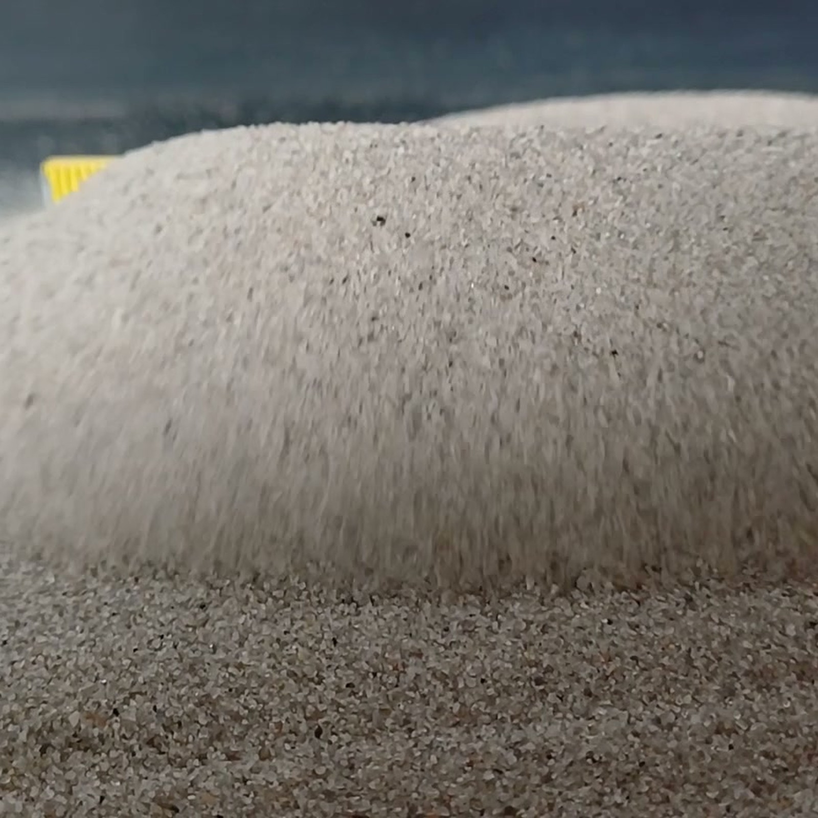 Aquariumsand Naturgrau, 0,1–0,5 mm, 10 kg: Steile Sandkante vor einer flachen Kornfläche.