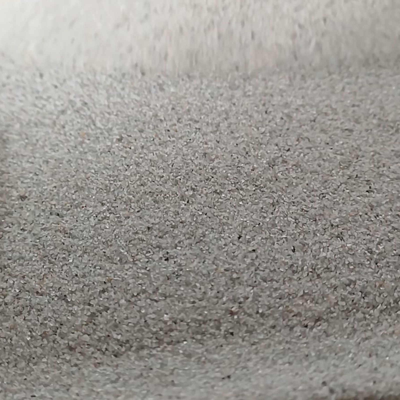 Aquariumsand Naturgrau, 0,1–0,5 mm, 19 kg: Flache graue Kornfläche in Nahaufnahme.