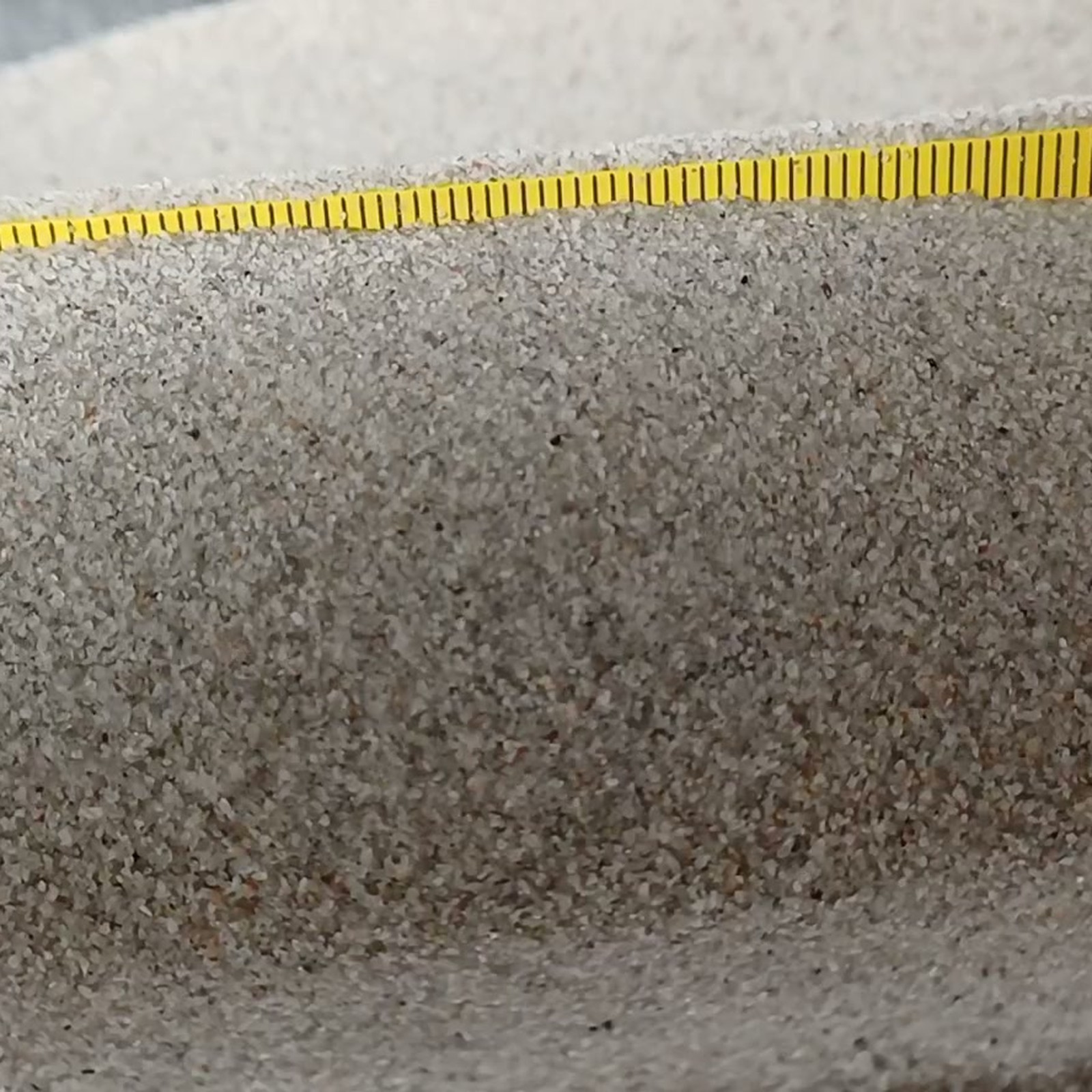 Aquariumsand Naturgrau, 0,1–0,5 mm, 19 kg: Erhöhter Sandrücken mit Maßstab dahinter.