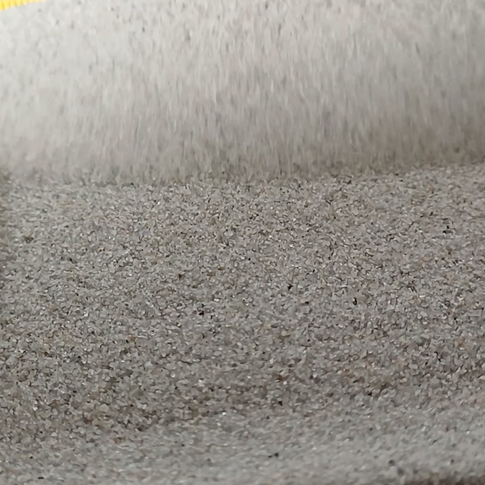 Aquariumsand Naturgrau, 0,1–0,5 mm, 19 kg: Zusätzliche Ansicht der Fläche vor einer hohen Sandkante.