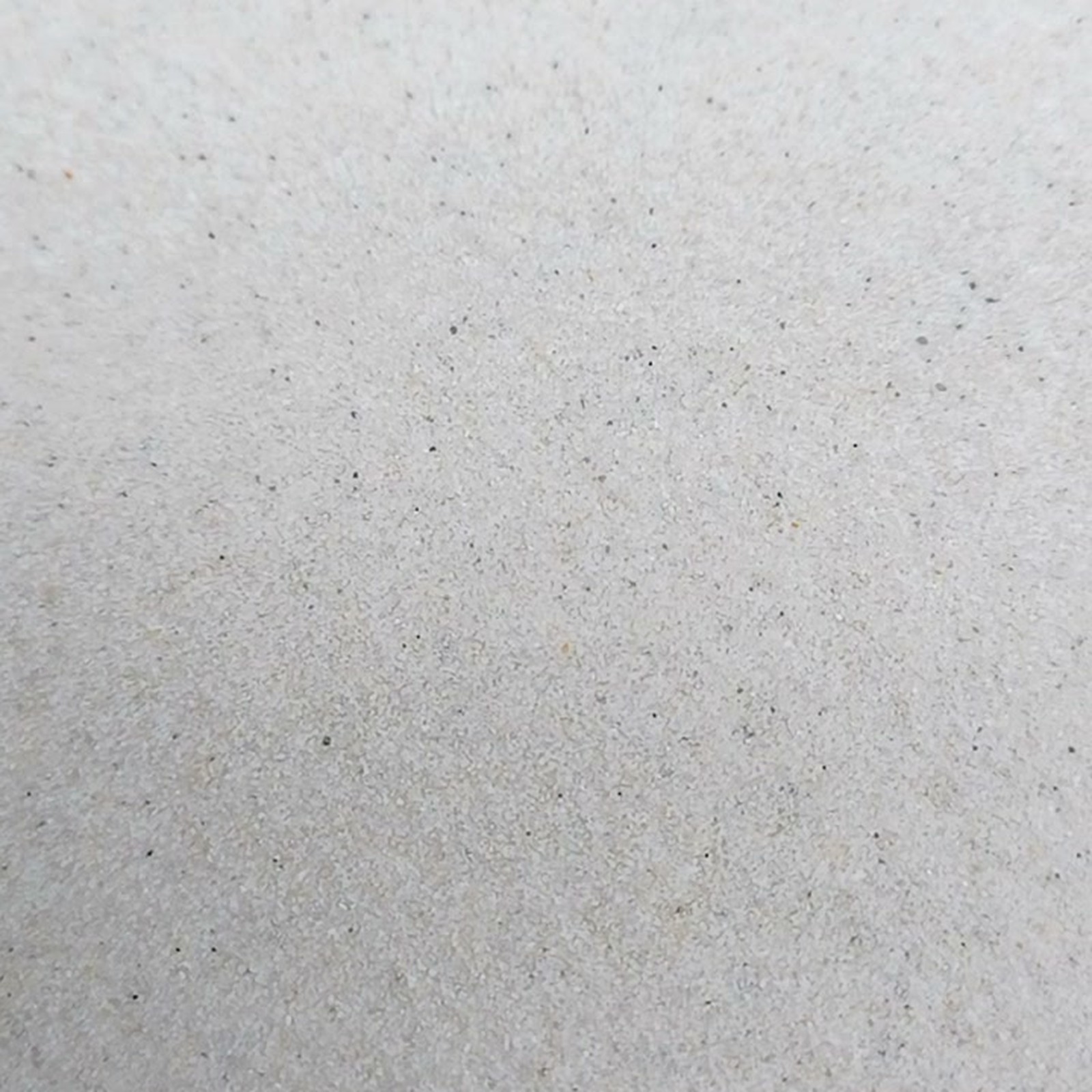Chinchillasand Naturweiß, 0,1–0,3 mm, 11 kg: Flache Sandfläche mit einzelnen dunklen Körnern.