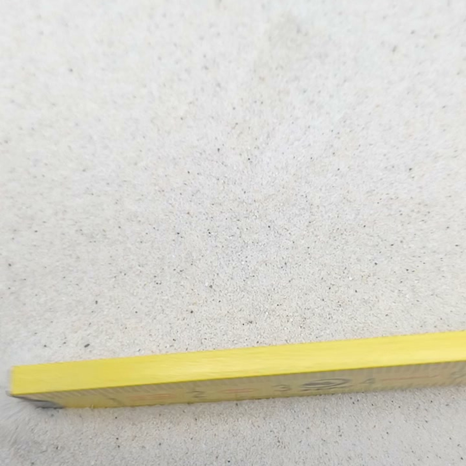 Chinchillasand Naturweiß, 0,1–0,3 mm, 11 kg: Sandoberfläche hinter einem gelben Maßstab.