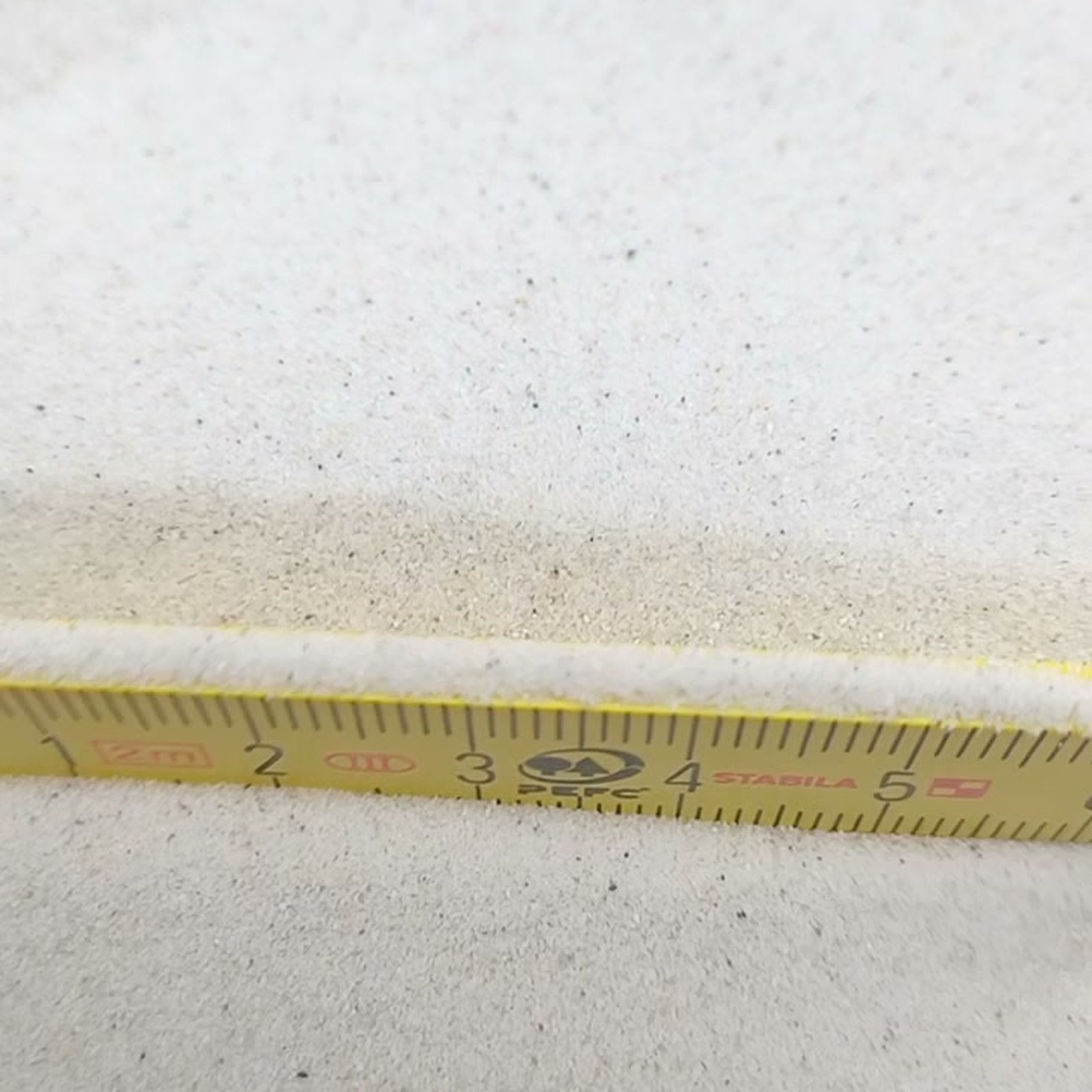 Chinchillasand Naturweiß, 0,1–0,3 mm, 11 kg: Sandkörner direkt hinter dem gelben Gliedermaßstab.