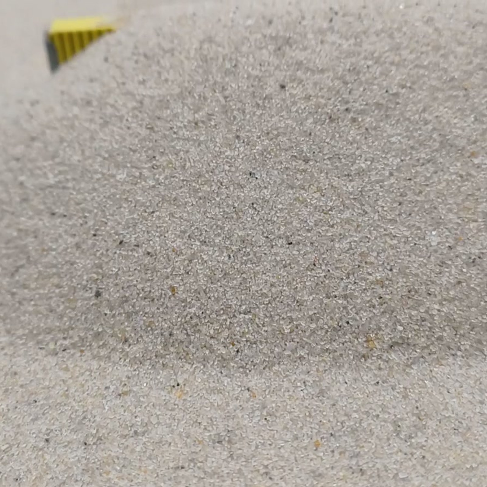 Chinchillasand Naturbeige, 0,1–0,3 mm, 25 kg: Sandrücken mit kleinem gelbem Maßstab am Bildrand.