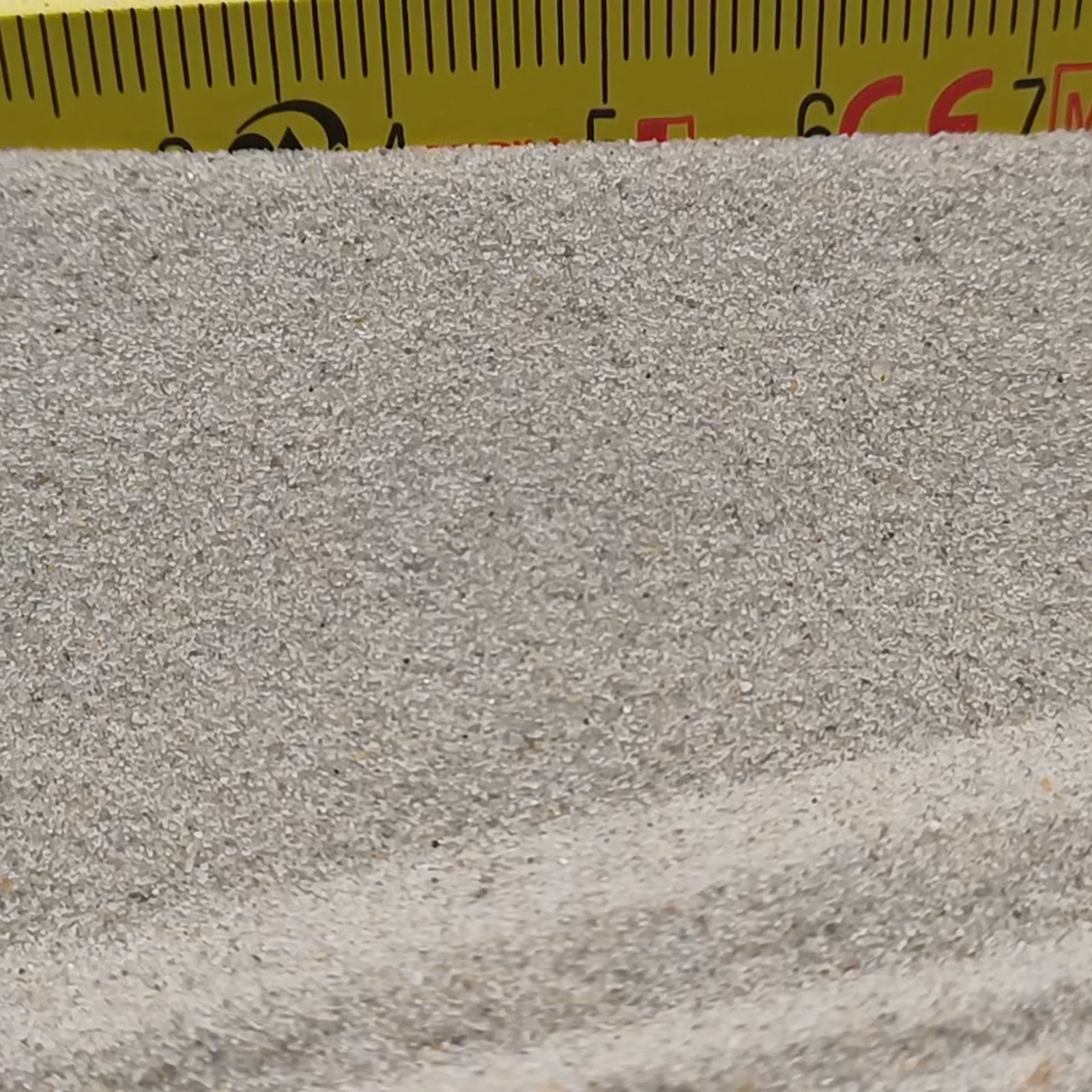 Chinchillasand Naturbeige, 0,1–0,3 mm, 25 kg: Gerade Sandkante direkt unter dem Maßstab.