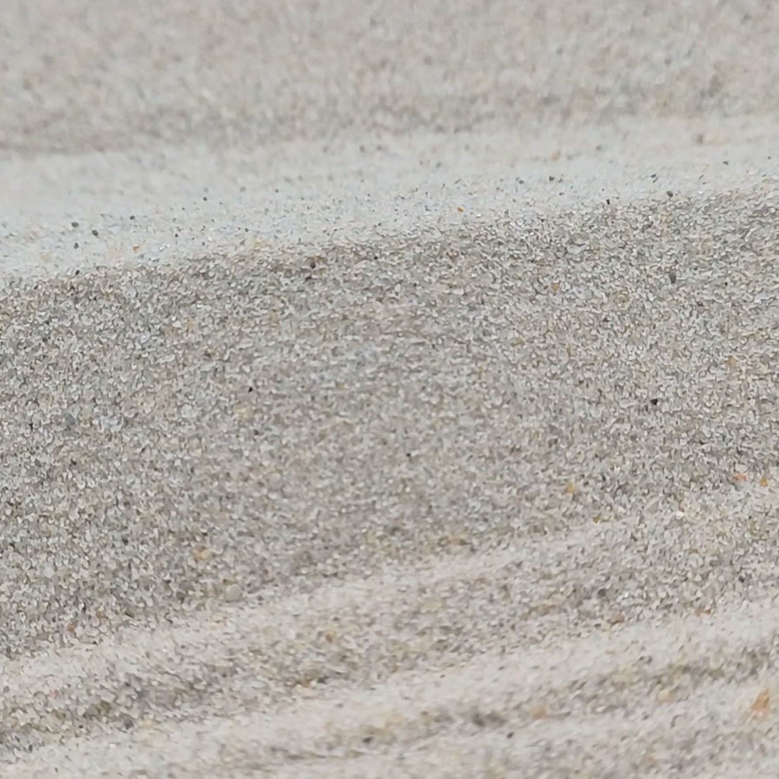 Chinchillasand Naturbeige, 0,1–0,3 mm, 25 kg: Erhöhte Sandkante mit sichtbarer Kornstruktur.