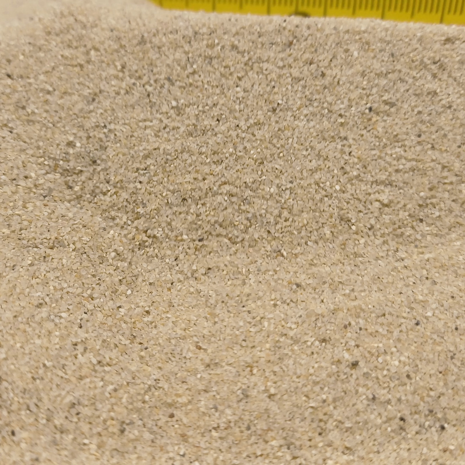 Terrariumsand Naturbeige, 0,3–0,6 mm, 25 kg: Flache Sandfläche mit Maßstab im Hintergrund.
